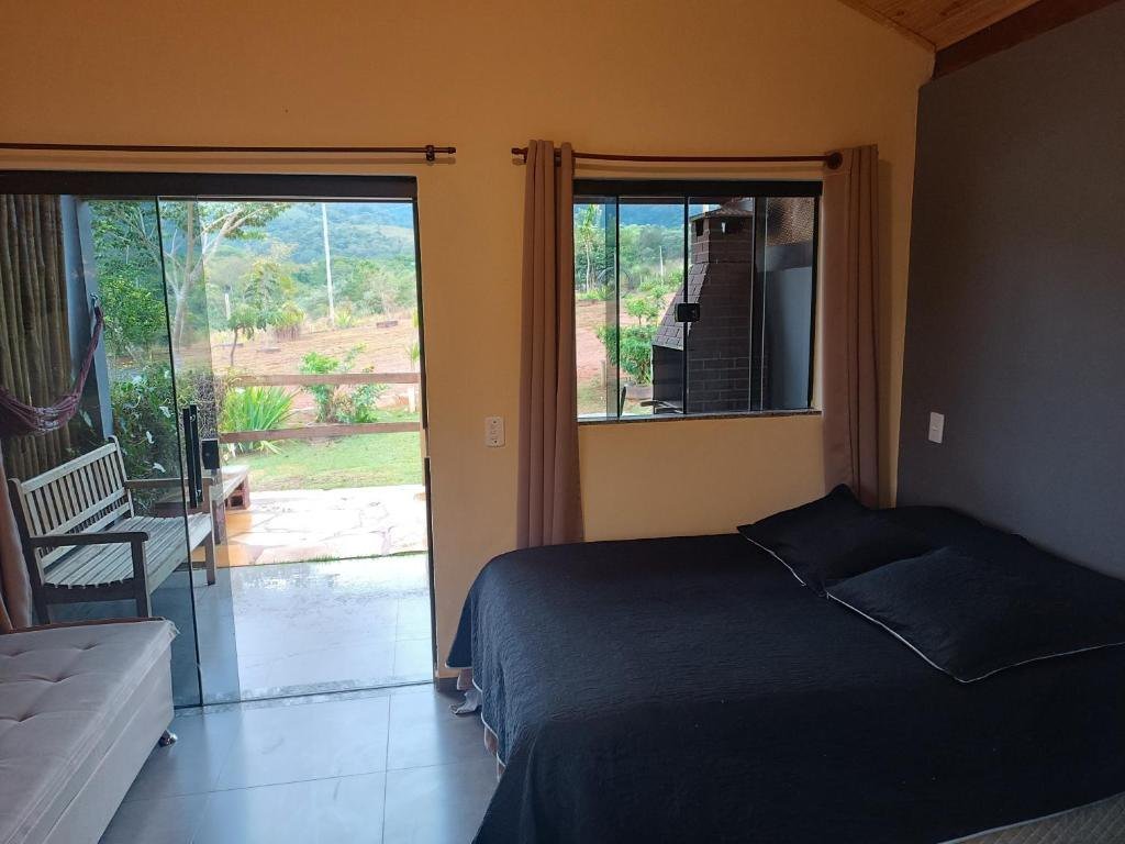 Interior do chalé com porta de vidro voltada para o jardim e a montanha
